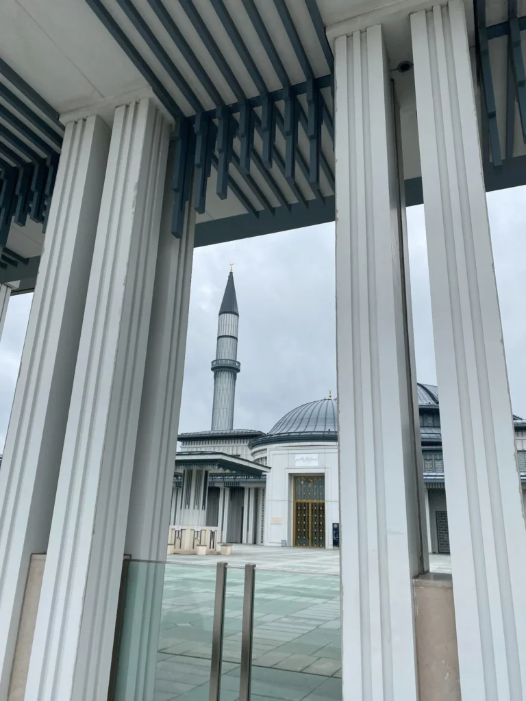 Ali Kuşçu Camii Nerede, Kimdir ve Neden Önemlidir? 6 Ali Kuşçu Camii'nin giriş bölümünden çekilmiş, sütunlar arasından minare ve ana kubbenin göründüğü bir fotoğraf. Modern mimari detaylar öne çıkıyor.