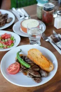 Çatalca'nın Lokal Yemek Yerleri ve Kasapları: Yerel Lezzet Durakları Rehberi 13 Çatalca'da servis edilen ızgara köfte tabağı, domates, biber ve kızarmış ekmek eşliğinde.