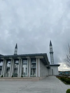 Ali Kuşçu Camii Nerede, Kimdir ve Neden Önemlidir? 15 Ali Kuşçu Camii'nin giriş bölümünden çekilmiş, sütunlar arasından minare ve ana kubbenin göründüğü bir fotoğraf. Modern mimari detaylar öne çıkıyor.
