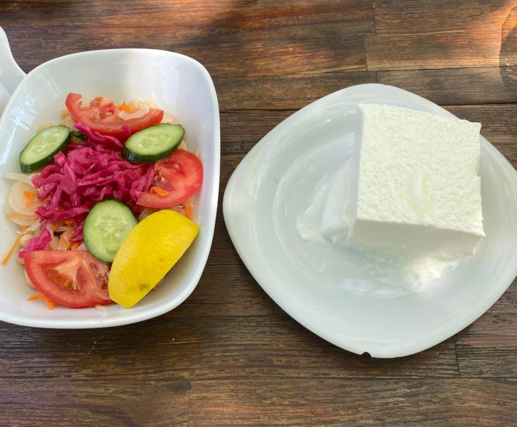 Tekirdağ’da Yol Üstü En İyi Köfte Nerede Yenir? | Esentepe Restoran 8 Domates, salatalık, turşu lahana ve limon dilimi içeren salata tabağı yanında doğal yoğurt.